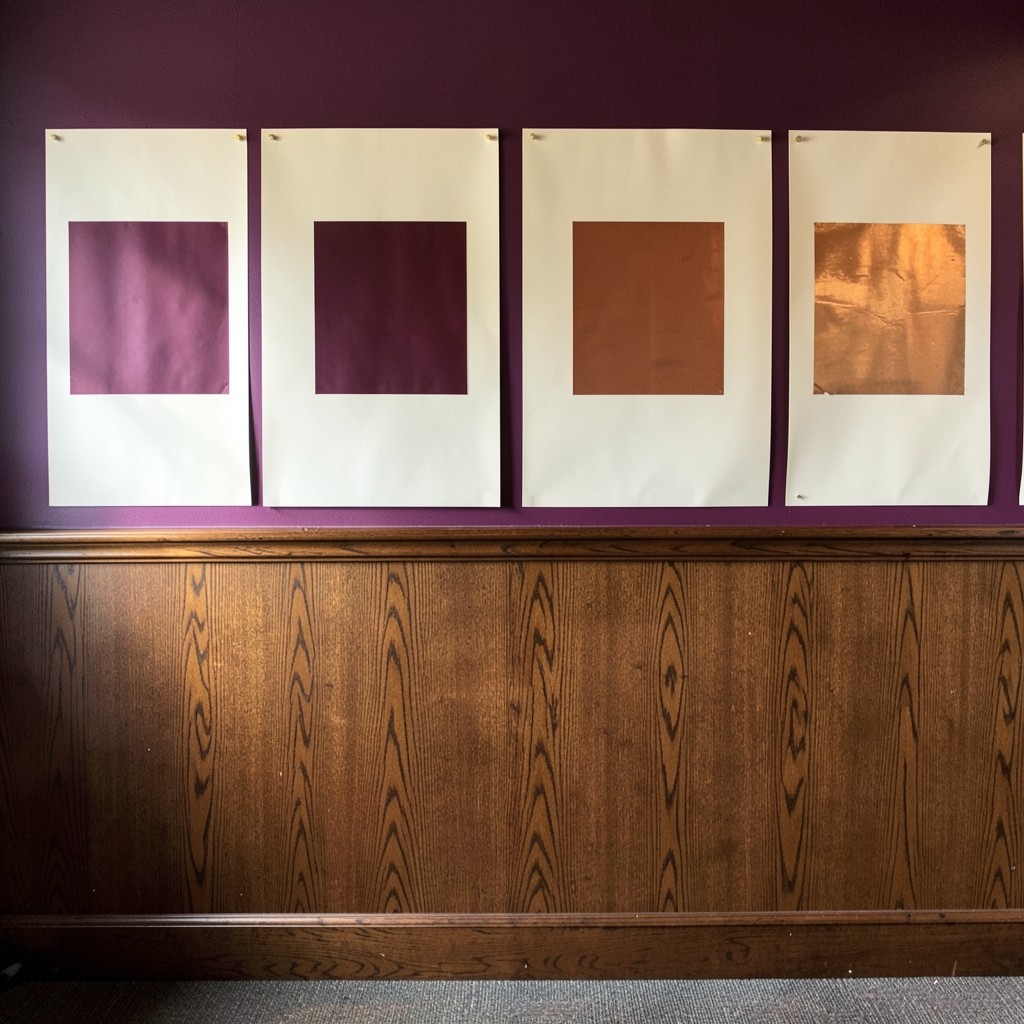Four large ivory sheets pinned in a row on a dark staff-room wall